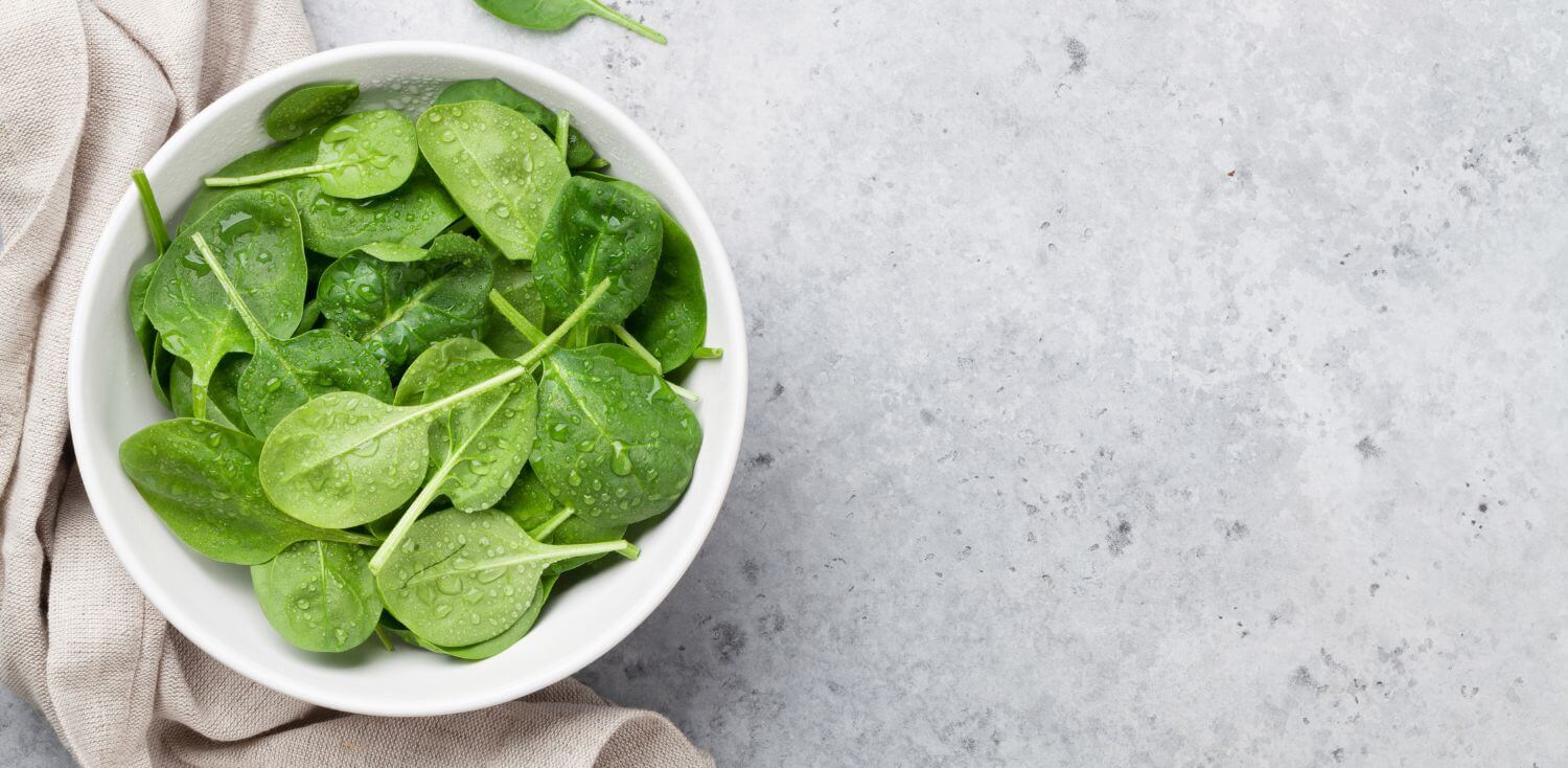 A white bowl filled with green leafy vegetables