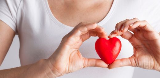 A woman holding a red heart in her hands.