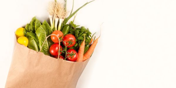 A brown paper bag filled with lots of vegetables