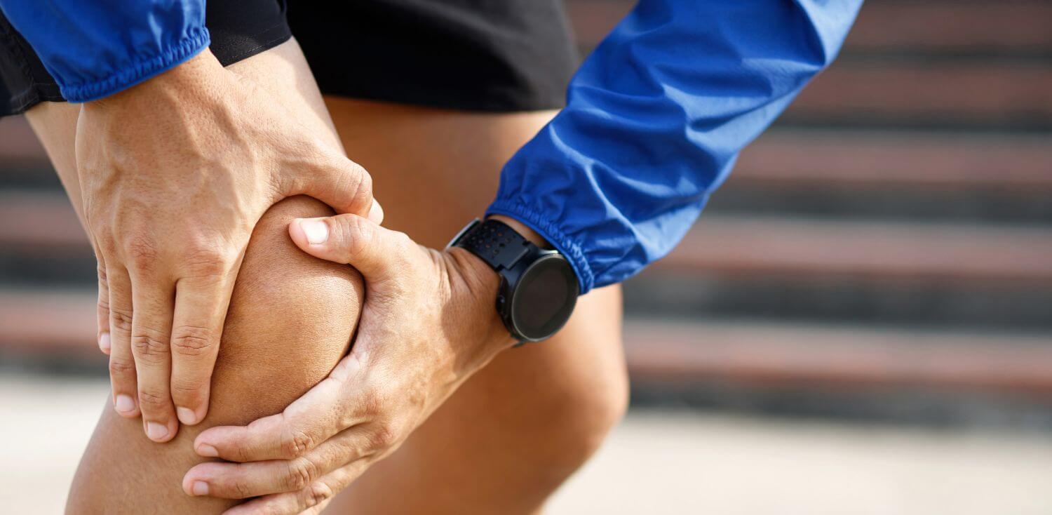 A close up of a person holding their aching knee