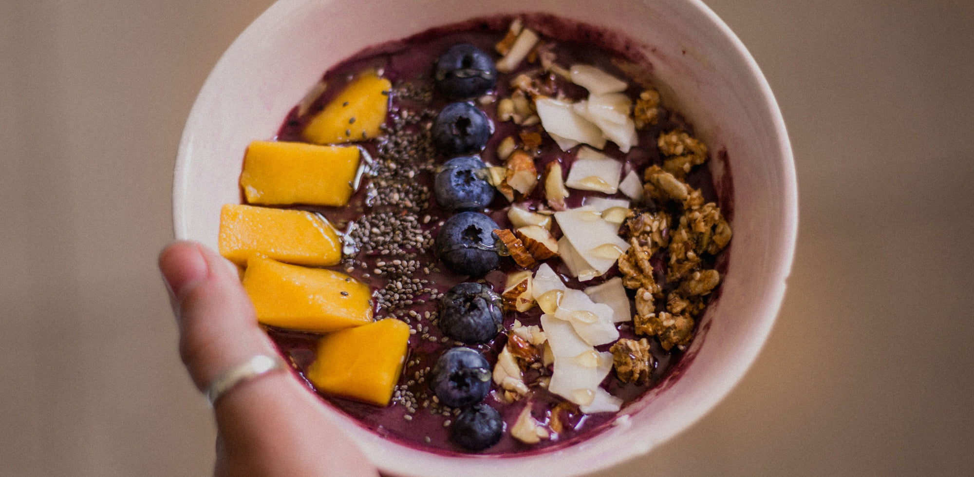 A person holding a bowl of fruit and granola.