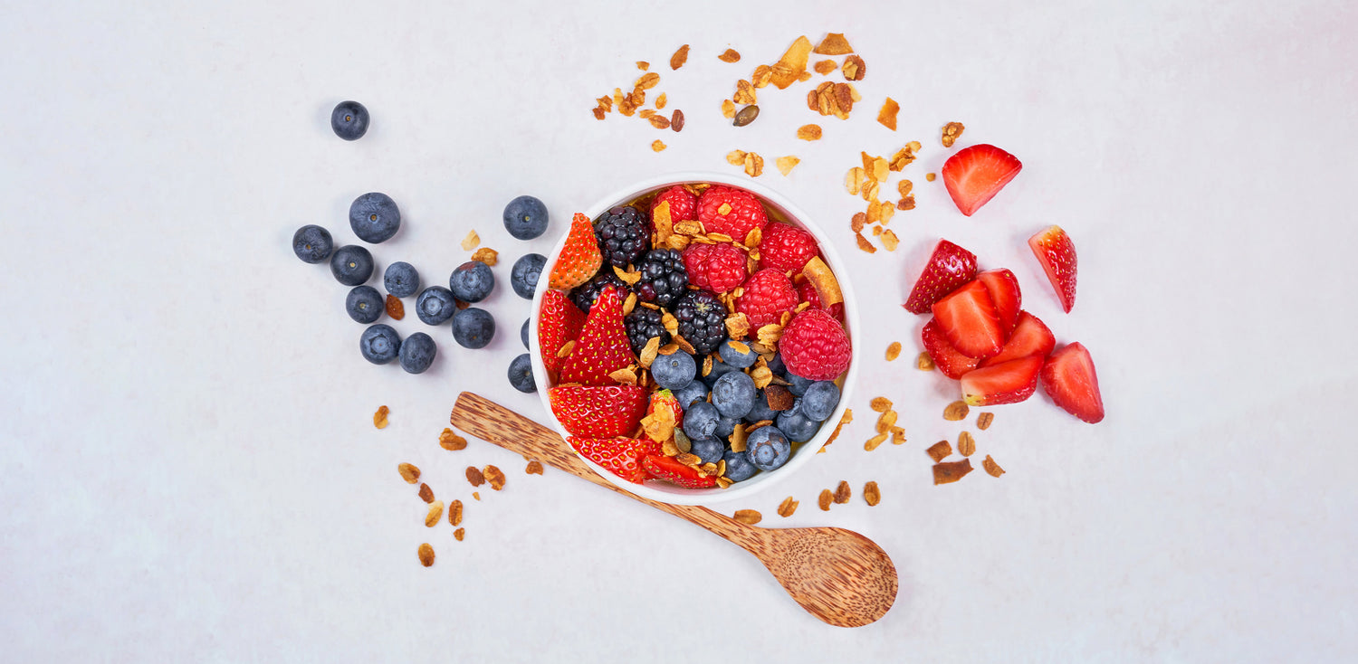 A bowl of cereal, strawberries, blueberries, and strawberries