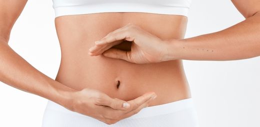 A woman in white underwear making a sign that draws attention to her stomach.