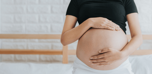 A pregnant woman holding her belly in her hands.