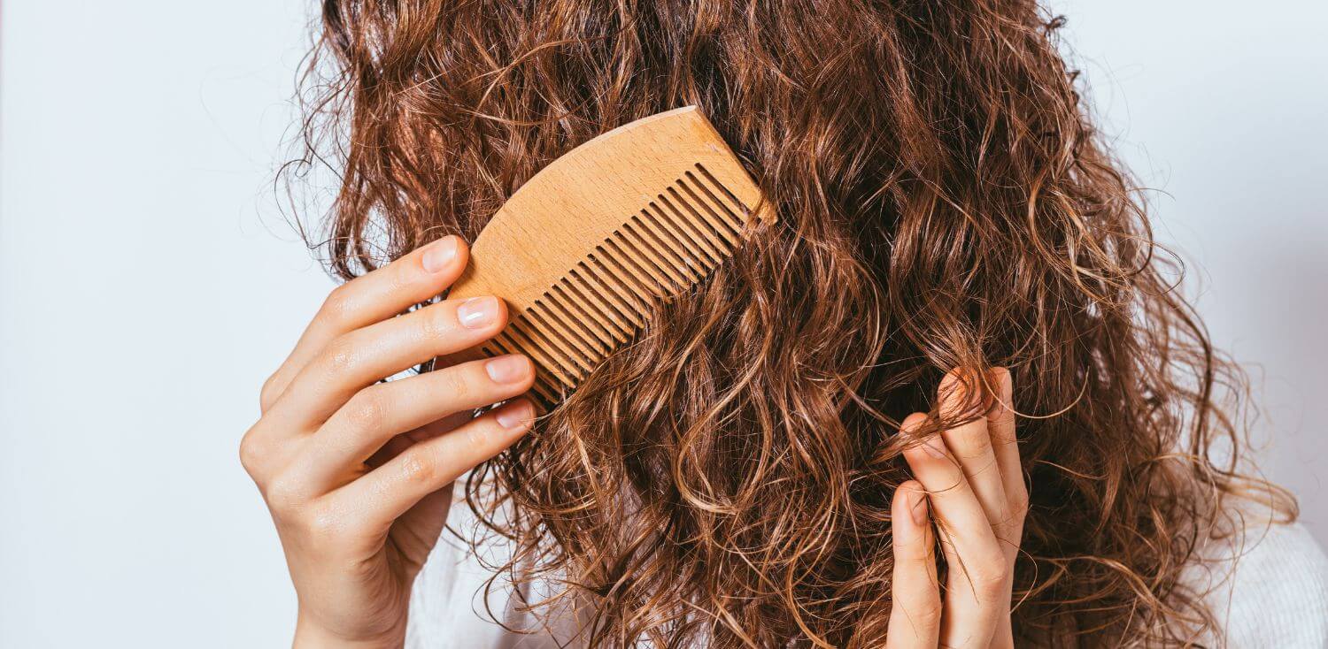A woman is combing her hair with a wooden comb