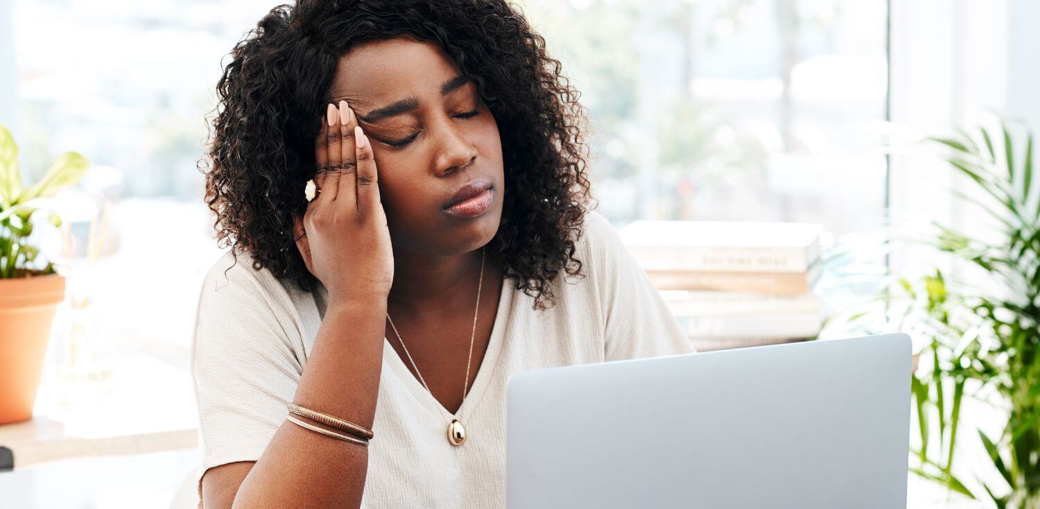 A woman looking stressed out sitting in front of a laptop computer.