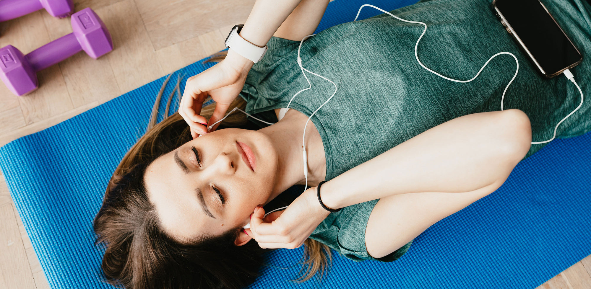 A woman laying on a yoga mat listening to music