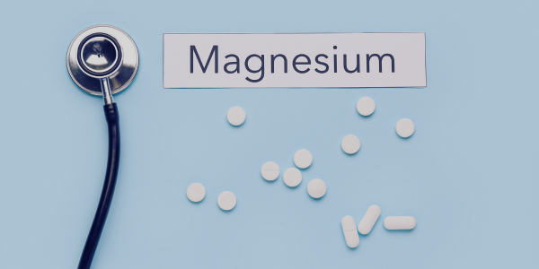 A stethoscope next to a sign that says Magnesium alongside some magnesium pills or capsules