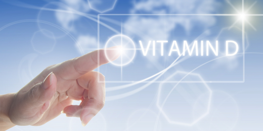 A human hand with an extended finger touching a glowing point on a transparent interface displaying the text "Vitamin D.