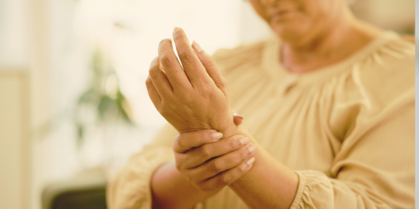 A person holding their wrist with both hands, appearing to experience pain or discomfort.
