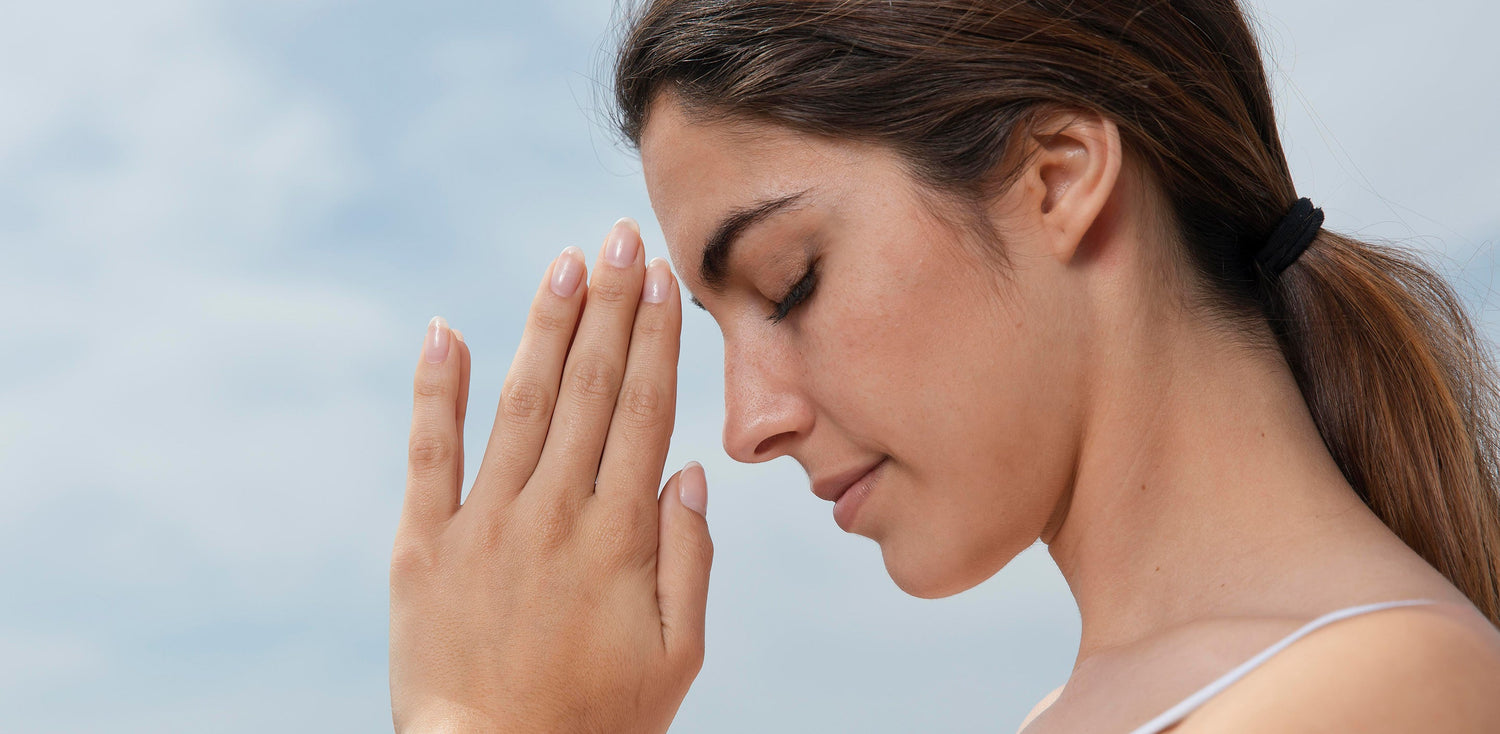 A woman holding her hands up to her face while meditating. 