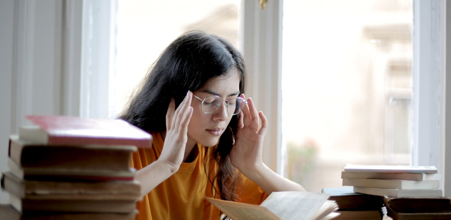 A woman looking stressed out sitting at a table with a book in front of her.