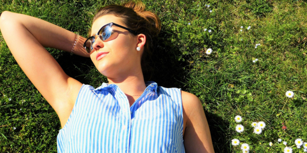 A woman laying in the grass wearing sunglasses.