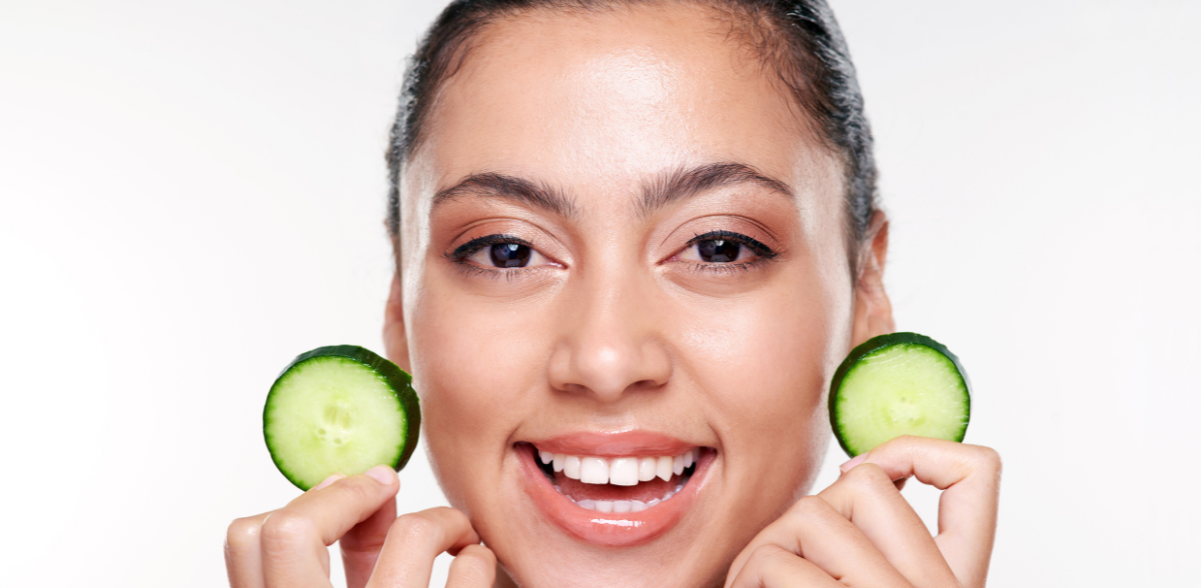 A woman holding two cucumbers over her face